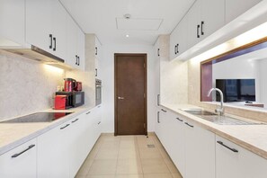 A modern kitchen with white cabinetry, a central door, and a built-in oven. - Exquisite and Capacious 1BR in South Ridge 3 (Dubai)