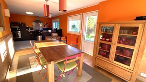 Una cocina con una mesa de madera, sillas y un armario con puertas de cristal.