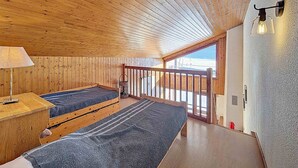 Una baita con interni in legno, due letti, un balcone e vista sulla spiaggia.