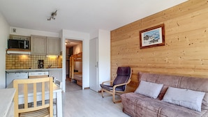Un espacio habitable compacto con kitchenette, un sofá y una silla.