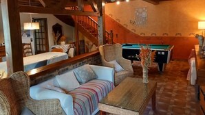 A cozy living room with a pool table, a sofa, and a dining area with a table and chairs. - Charming Cottage with Spa, Billiards, Garden and Ping-Pong (Vinon)