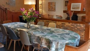 A dining area with a table set for four, a vase with flowers, and a brick wall with artwork. - Charming Cottage with Spa, Billiards, Garden and Ping-Pong (Vinon)