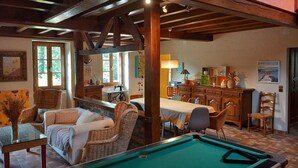A cozy living room with a pool table, comfortable seating, and a dining area with a view of the outdoors. - Charming Cottage with Spa, Billiards, Garden and Ping-Pong (Vinon)