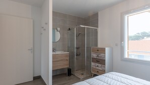 Une chambre moderne dotée d’un grand lit, d’un dressing, d’une salle de bain avec douche et d’une fenêtre offrant une belle vue.