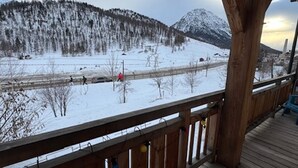 A wooden deck with a view of a snowy landscape and mountains.