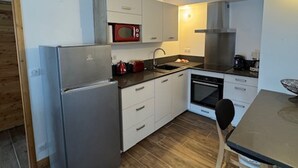A compact kitchen with a refrigerator, microwave, stove, and sink.