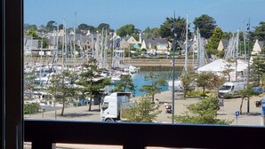 Un puerto deportivo con barcos, un camión y una vista de casas al fondo.
