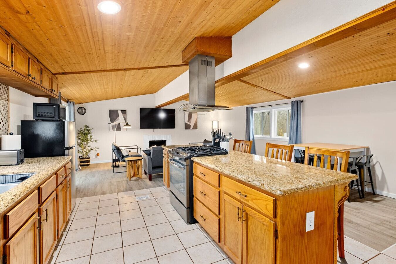 A modern kitchen with wooden cabinets, a central island, and a built-in stove.