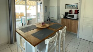 Une cuisine compacte avec un coin repas, des meubles blancs, un four à micro-ondes et une machine à café.