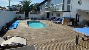 Une maison moderne dotée d’une piscine, d’une terrasse en bois et de chaises longues.