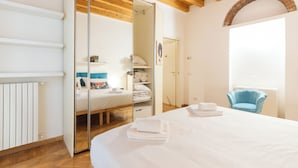 Une chambre avec un grand lit, une armoire et un fauteuil bleu.