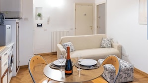Un espace de vie compact comprenant un coin repas, une kitchenette et un canapé.