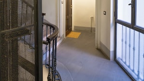 Un couloir avec un escalier, une porte donnant sur une autre pièce et une grande fenêtre.