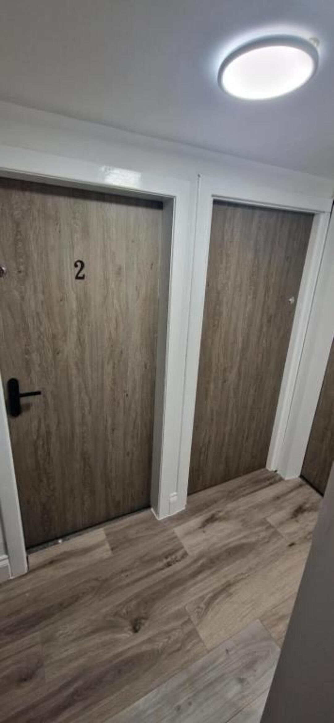 A hallway with two wooden doors, each marked with a number.