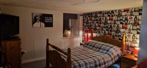 A bedroom with a bed, a TV, a wardrobe, a window with a view of the street, and a wall decorated with clocks and other images. - High Street Apartment Getaway in Inverurie (Inverurie)