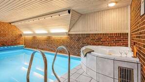 An indoor swimming pool with a wooden ceiling and brick walls.