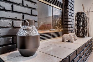 Un interno moderno con una parete in mattoni scuri, un vaso decorativo di grandi dimensioni e una piccola statuina di elefante su una superficie piastrellata.