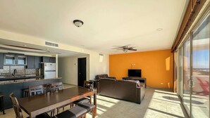 A modern apartment with a dining area, kitchen, living room, and a balcony with a view.