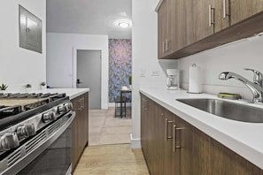 A modern kitchen with wooden cabinets, a stainless steel sink, and a gas stove.