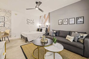A modern living room with a bed, sofa, coffee table, and a ceiling fan. - Steps from Sand | Coastal Retreat Stylish Studio (Miami Beach)