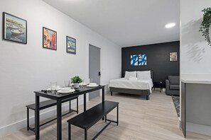 Ein modernes Hotelzimmer mit einem Bett, einem Esstisch mit Stühlen, einer Bank und Wandbildern.