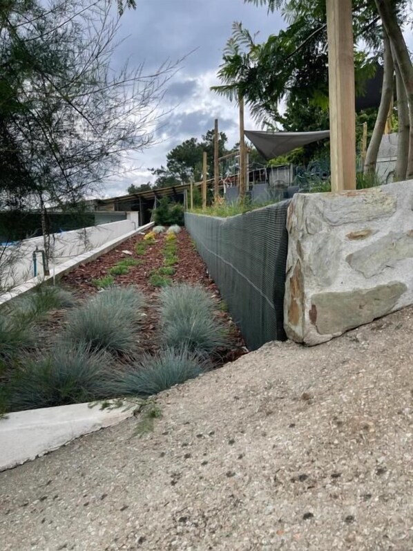 A landscaped garden with a stone retaining wall, a gravel path, and a variety of plants. - La Cigarrita Guest House - Douro Valley (Peso da Régua)