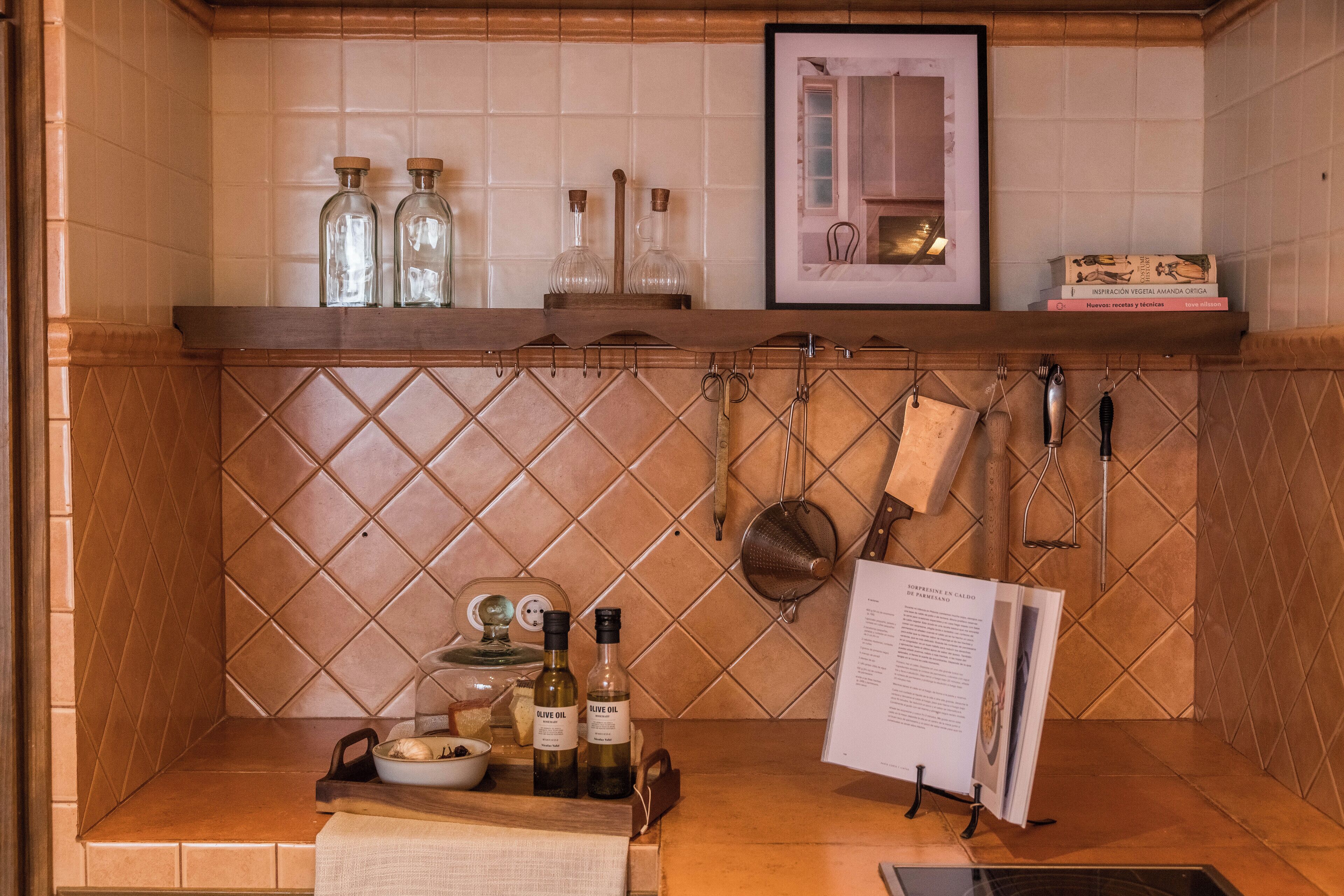 A kitchen with a tiled backsplash, a wooden countertop, and various kitchen utensils and bottles.