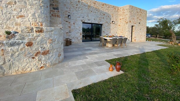 Edifici de pedra amb pati, taula de dinar i dues gerres.