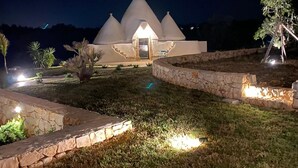 Un edifici modern amb una estructura cònic única, envoltat de camins ben il·luminats i petits arbres.