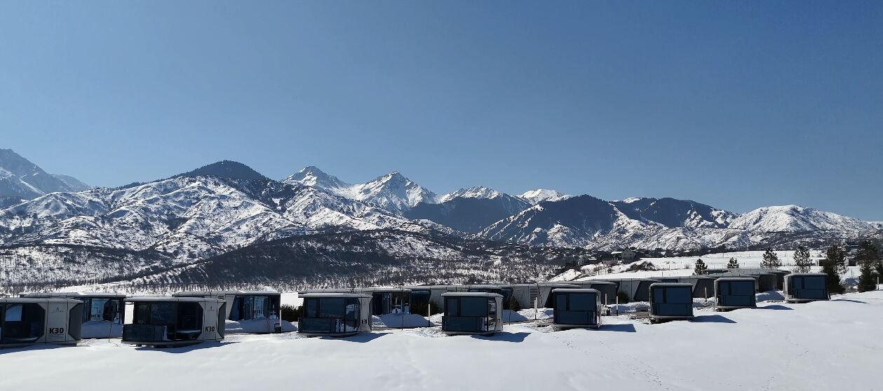 Une rangée de cabanes avec une montagne enneigée en arrière-plan.