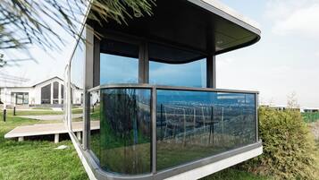 Een moderne, gebogen glazen structuur met uitzicht op een stadsbeeld.