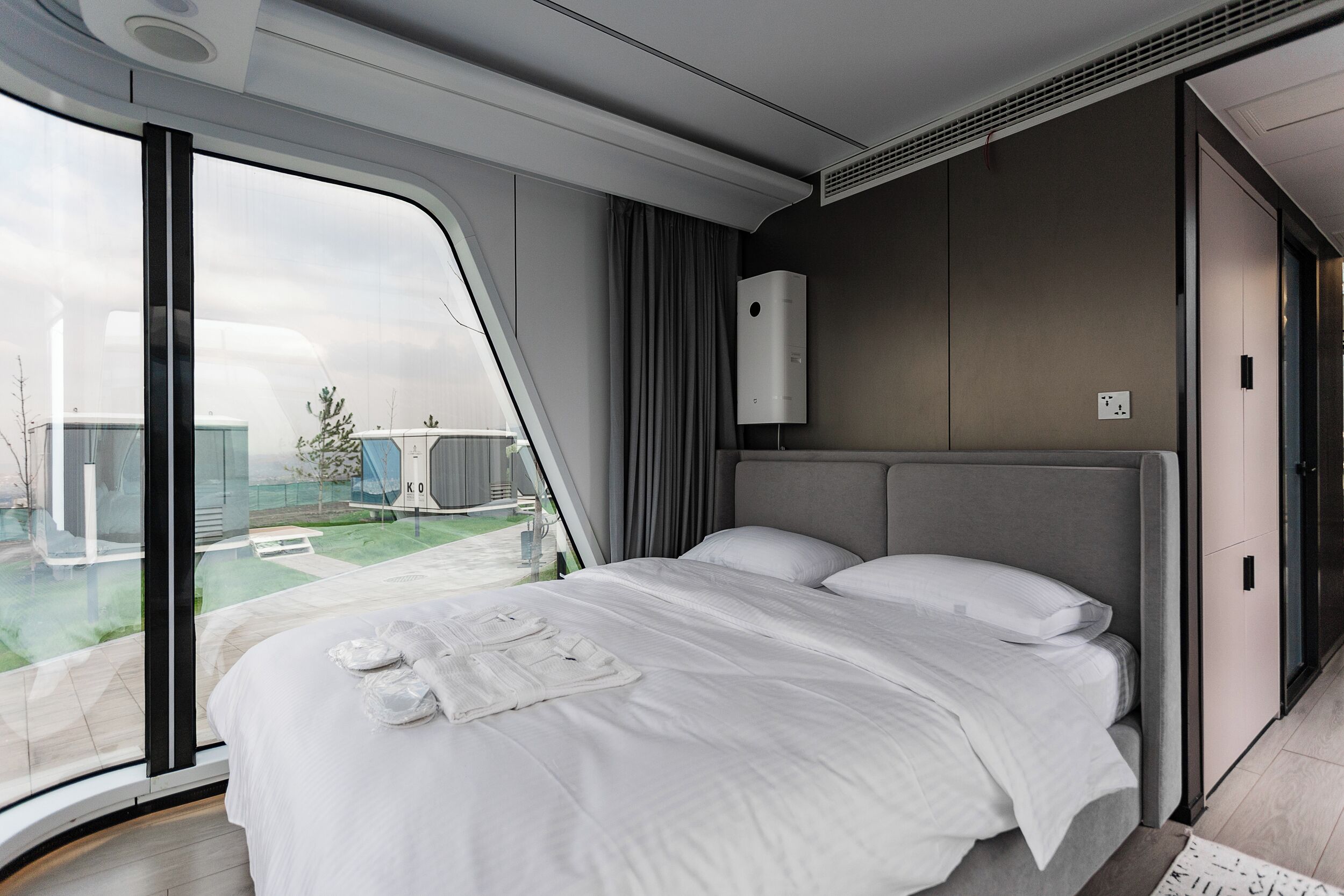 Habitación de hotel moderna con una cama grande, vistas al exterior y aire acondicionado integrado.