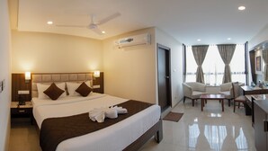 Una habitación de hotel con una cama grande, un escritorio, una silla y un ventilador de techo.