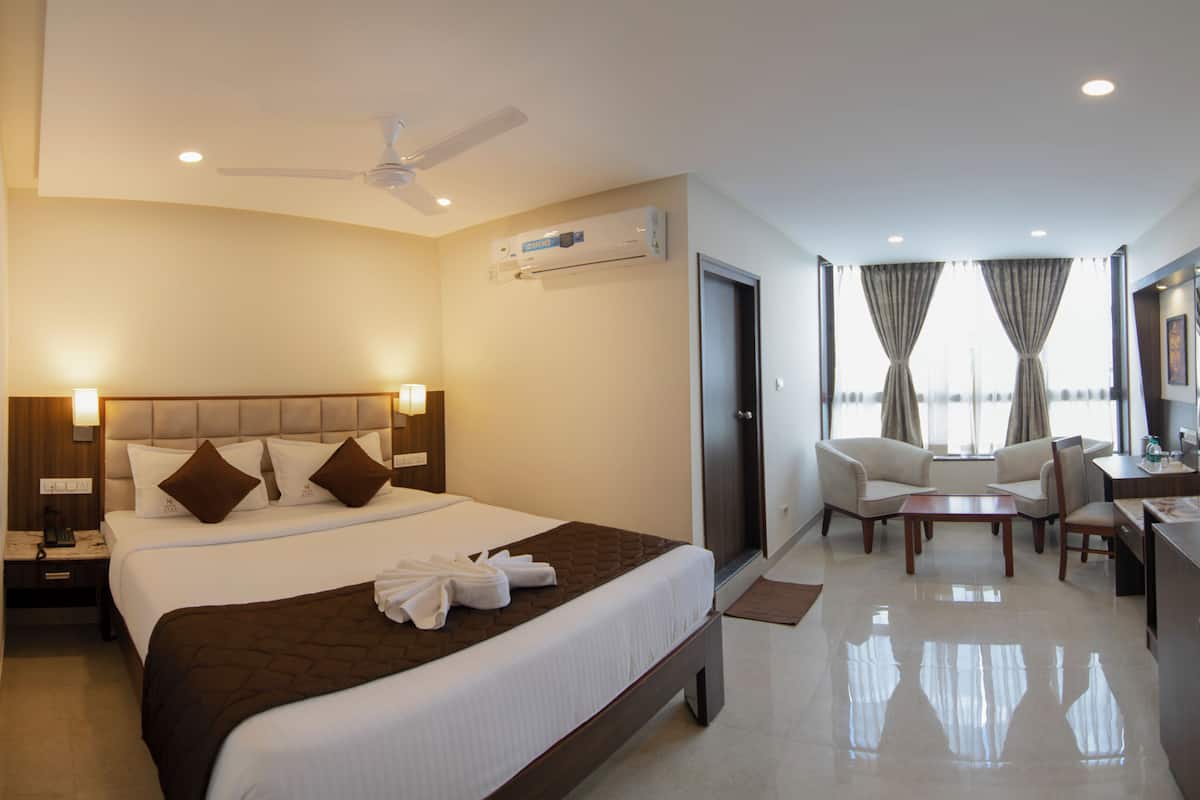 Ein Hotelzimmer mit einem großen Bett, einem Schreibtisch, einem Stuhl und einem Deckenventilator.