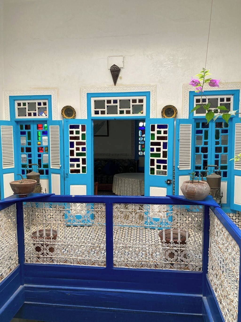 A blue and white room with a bed, a small table, and a potted plant.