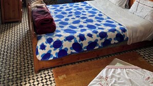 A bedroom with a bed, a chair, a small table, a wooden cabinet, and a window with curtains. - 2 BEDROOM APARTMENT WITH SEAVIEW IN THE MEDINA (Essaouira)