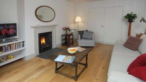 A living room with a fireplace, a sofa, a coffee table, and a television.