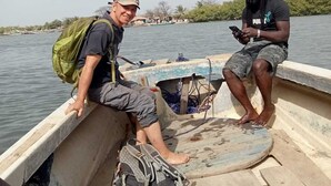 Twee mensen in een boot, met een groene rugzak en een grijze tas.