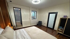 Une chambre à coucher avec un grand lit, une chaise, une armoire et une porte donnant sur une autre pièce.