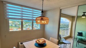 Un comedor con una mesa y sillas, un lámpara colgante y vistas a través del ventanal.