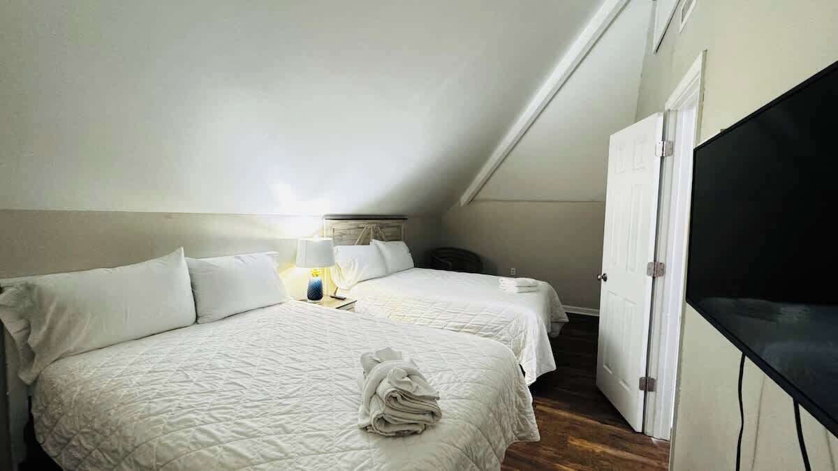 Una habitación de hotel con dos camas, un televisor y un armario.