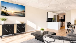Ein modernes Wohnzimmer mit einem schwarzen Marmortisch, einem schwarz-goldenen Schrank und einem großen gerahmten Bild von Myrtle Beach.