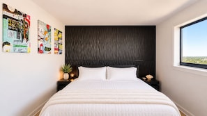 A bedroom with a bed, a dark headboard, a nightstand with a plant, and a window with a view. - Ocean Villas apartment, view the ocean and relax (Myrtle Beach)