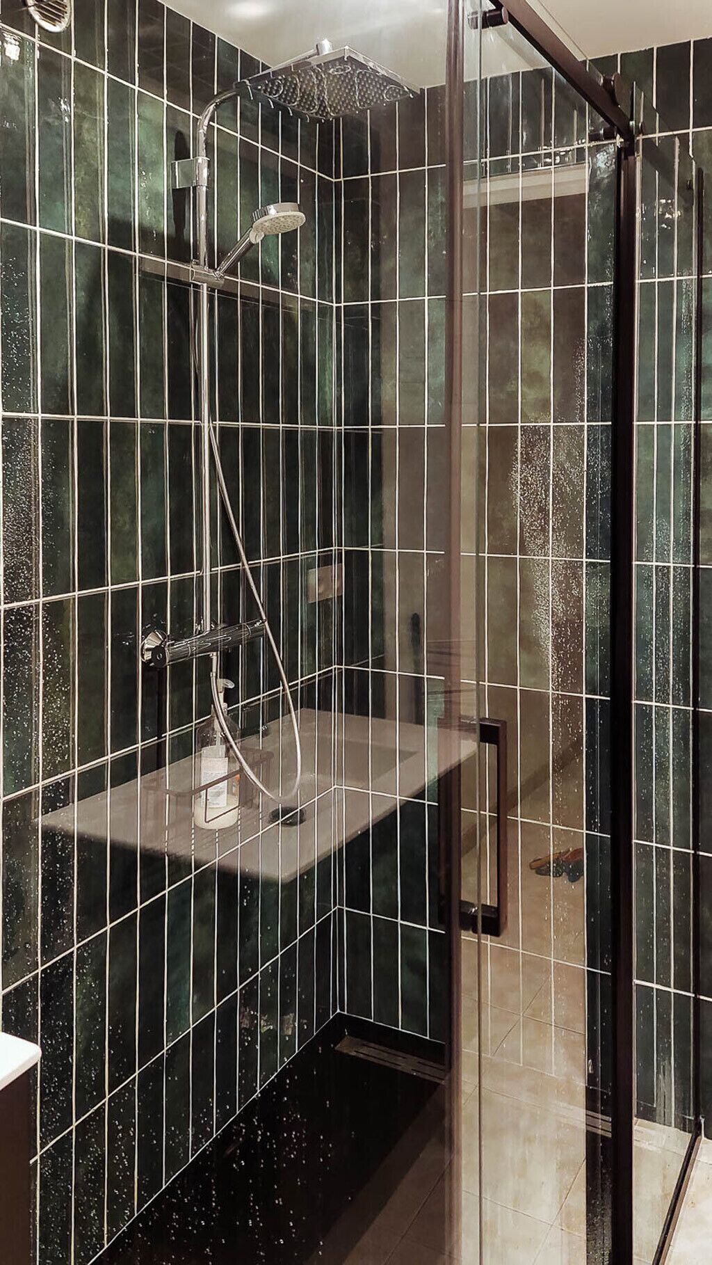 Une douche moderne dotée d’une paroi en verre, d’un pommeau de douche à main et d’un robinet mural.