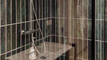 Une douche moderne dotée d’une paroi en verre, d’un pommeau de douche à main et d’un robinet mural.