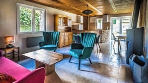 Amplia sala de estar con sillones color turquesa, una mesa de madera y una chimenea de piedra.