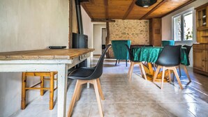 Un comedor rústico con una mesa y sillas de madera, una pared de piedra y vistas al exterior.