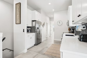 Una cocina moderna con armarios blancos, un refrigerador de acero inoxidable y un reloj en la pared.