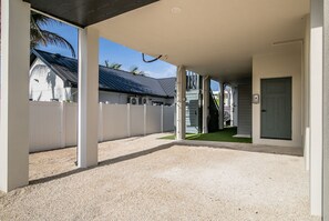 An open covered area with a gravel floor, white walls, and a door to the right.