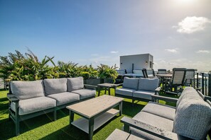 Eine Dachterrasse mit Gartenmöbeln, einem Tisch und einem kleinen Gebäude.